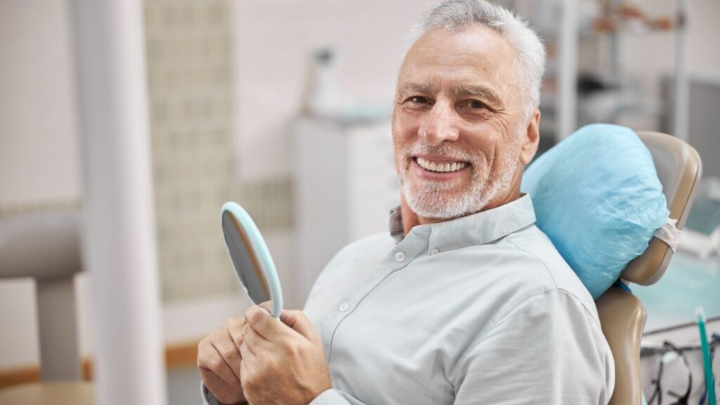 Man Smiling While Sitting in a Dentist Office